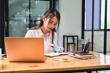 Young Asian woman working with laptop computer in office.