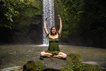 Yoga lotus pose. Caucasian woman sitting on the stone, meditating, practicing yoga, pranayama at...