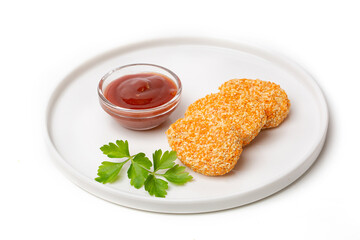 A pile of cooked chicken nuggets in a plate with tomato sauce, isolated on a white background