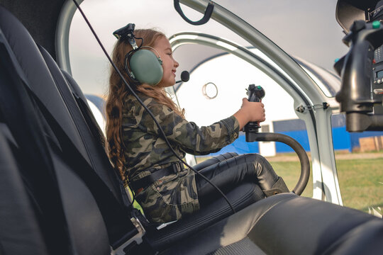 Cheerful girl in pilot headset sitting in helicopter cockpit