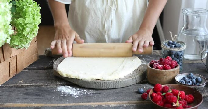 Woman Hands with rolling-pin make dough for pierogi. cooking preparation process on wood table.