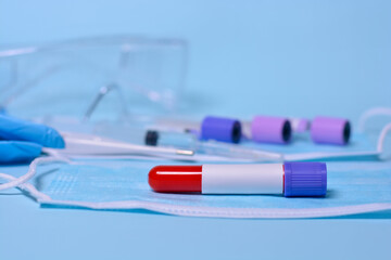 A test blood sample tube . A test tube on a medical mask against the background of test tubes, thermometer, syringe, medical glasses