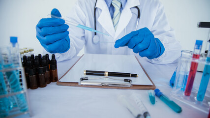 Fototapeta premium medical or scientific researcher researching and experimenting Multi-colored solution, vial and microscope In the laboratory or in the laboratory by wearing blue gloves and white clothing completely.
