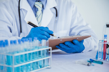 medical or scientific researcher researching and experimenting Multi-colored solution, vial and microscope In the laboratory or in the laboratory by wearing blue gloves and white clothing completely.