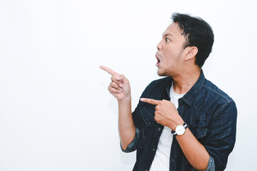 Young asian man is surprised and shouting wow with pointing right with his hand isolated on gray...