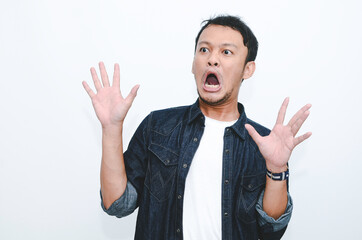 Young asian man is surprised and shouting wow with pointing right with his hand isolated on gray...