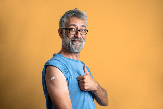 portrait of a happy man after vaccination, thumb up for the, administration of anti-covid19 vaccine, isolated man on yellow orange background with copy space