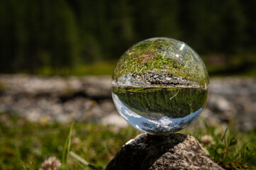 Obraz na płótnie Canvas Glass sphere lying on a rock, river in Austrian alps