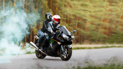 Motorcyclist in protective gear and helmet sitting with a girl on a sports motorcycle on a blurred background with smoke, copy space