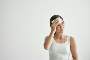 woman in white t-shirt wipes her forehead with a handkerchief pain head health problem