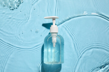 Bottle of cosmetic product in water on color background