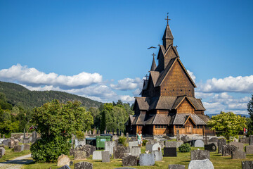 Graveyard at the Heddal Stave Church in Notodden, Norway surrounded by green hills on a sunny day