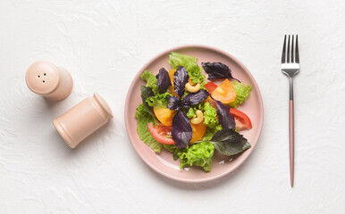 Plate with tasty fresh salad and spices on light background