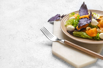 Plate with tasty fresh salad on light background