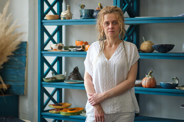 confident business owner posing in her office. in the background a wardrobe with ceramic dishes