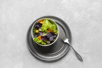 Bowl with tasty fresh salad on light background