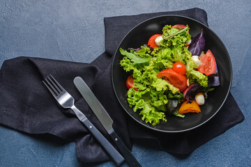 Bowl with tasty fresh salad on dark background