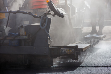 close-up view of asphalting paver machine during road street repairing works at day light with...