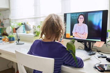 Obraz premium Child preteen girl studying at home using video lesson on computer