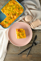 Plate with piece of mashed potato casserole on wooden background