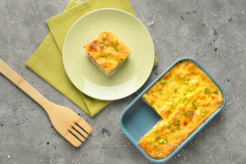 Plate and baking dish with mashed potato casserole on grunge background