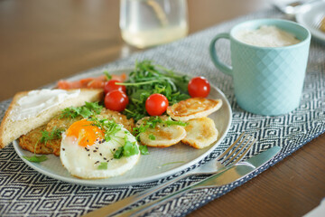 Cozy homemade breakfast: potato pancakes with scrambled eggs, red fish, cheese and vegetables with herbs