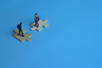 Business mergers and acquisitions, partnership concept. Two miniature people merging on puzzle....