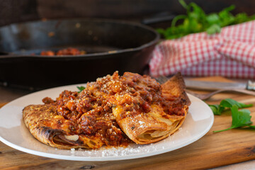 Italian cuisine - filled pancakes or crespelle with bolognese sauce and parmesan cheese