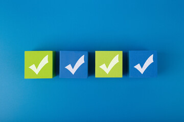 Creative flat lay with four checkmarks on blue and yellow toy cubes with in the middle of blue...