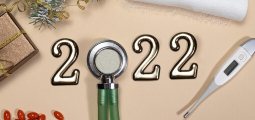 New Year 2022 medicine. Long banner on medical subjects: phonendoscope, thermometer on a beige background.