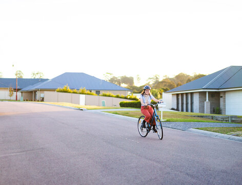 Quiet street in housing area of town with female riding bike for exercise