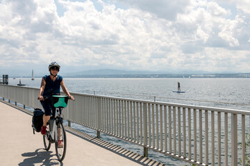 Erholung am Bodensee mit dem Fahrrad, Frau mit Elektro Fahrrad bei schönem Sommer Wetter unterwegs.