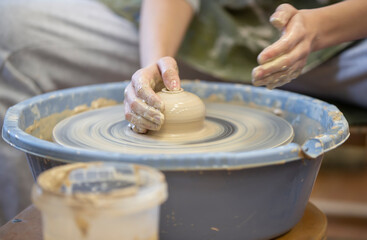 Close-up of a potter's hands with an item on a potter's wheel. Working with clay. Clay workshop. Craft training.