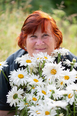 Beautiful elderly woman with a bouquet of daisies smiling and looking at the camera.