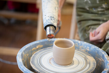 Fototapeta na wymiar Clay vase on a potter's wheel. Working with clay