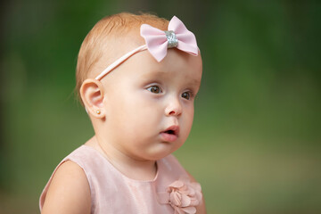 The face of a beautiful little girl on a green background. One year old child.