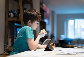 Healthy boy eating red apple for his snack after finished homework,New normal life kid using tablet...