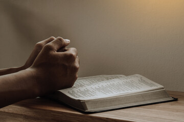 Hands of a man praying over a Bible at home.Chruch online,chruch at home.
