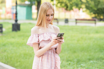 Happy and attractive blonde girl holding a smartphone. Online working. Freelance