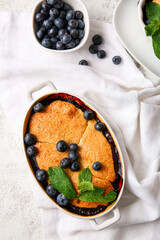 Baking dish with blueberry cobbler on light background