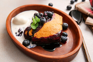 Plate with piece of blueberry cobbler and ice cream on light background, closeup