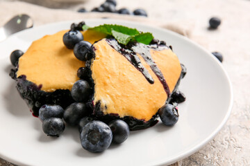 Plate with pieces of blueberry cobbler on light background, closeup