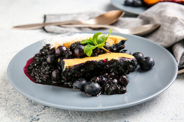 Plate with pieces of blueberry cobbler on light background, closeup