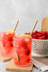Glasses of cold raspberry lemonade on table