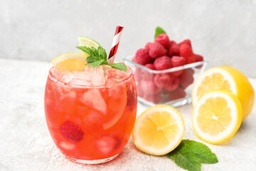 Glass with tasty raspberry lemonade on light background