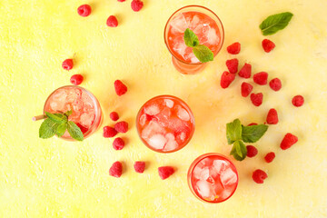 Glasses of delicious lemonade and raspberries on color background