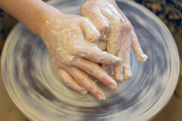 Potter's hands at work. Close-up of a potter's hands with a product on a potter's wheel. Working with clay.