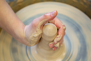 Potter's hands at work. Close-up of a potter's hands with a product on a potter's wheel. Working with clay.