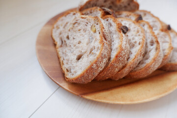 Close-up image of a bread cutting on a Wooden dish and white wood background. Healthy baked bread, whole bread on dark background.