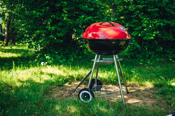 Red Outdoor grill in a park with greenery
